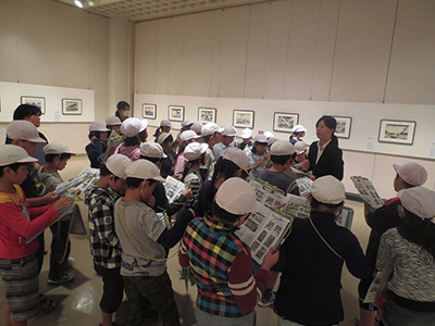 学芸員から展示についてのお話を聞いています。