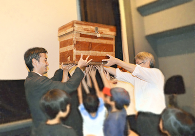 母子生活支援施設の母子と,ワークショップで制作した成果物や手紙をタイムカプセルに封印するようす