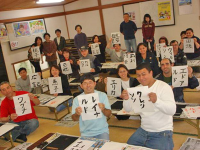 写真：書道体験 学習者が書きあがった半紙を掲げているところ